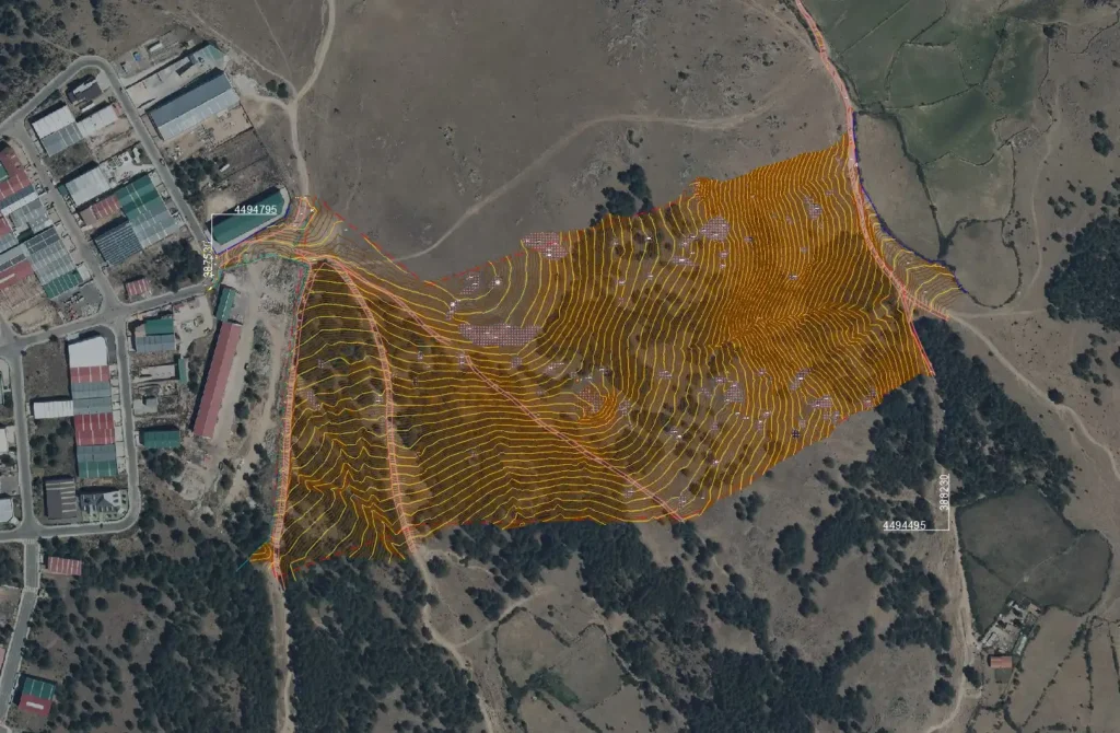Vista aérea de un terreno con curvas de nivel marcadas, delimitado por puntos naranjas rodeado de áreas de cultivo y vegetación.
